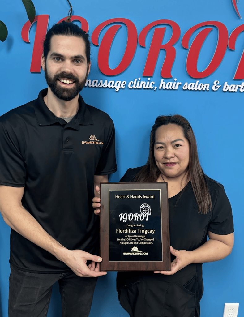 Liza, Registered Massage Therapist in Edmonton, holding the Heart and Hands Award plaque with Spamarketing.com co-founder Riley Cassidy